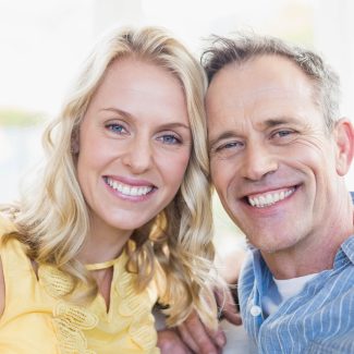 Happy,Couple,Smiling,At,Camera,In,The,Living,Room